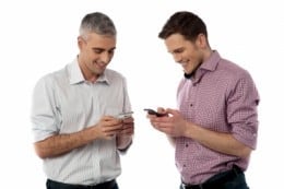 smiling men using smart phones
